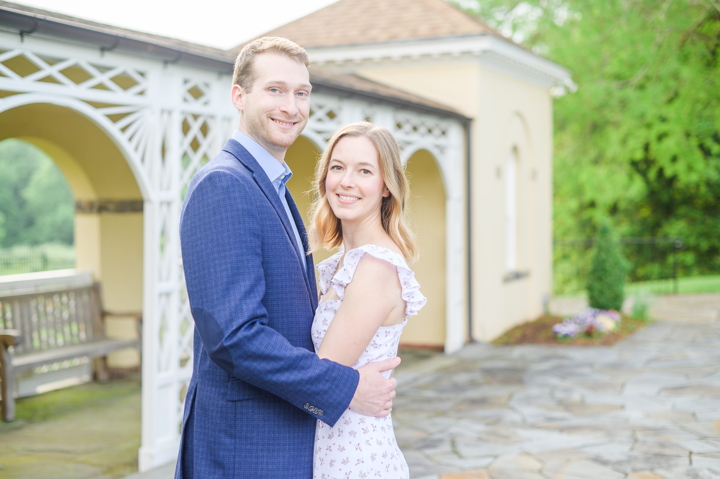 Engaged Couple smiles in the garden at Belmont Manor during a rainy sunset engagement photographed by Baltimore Wedding Photographer Cait Kramer