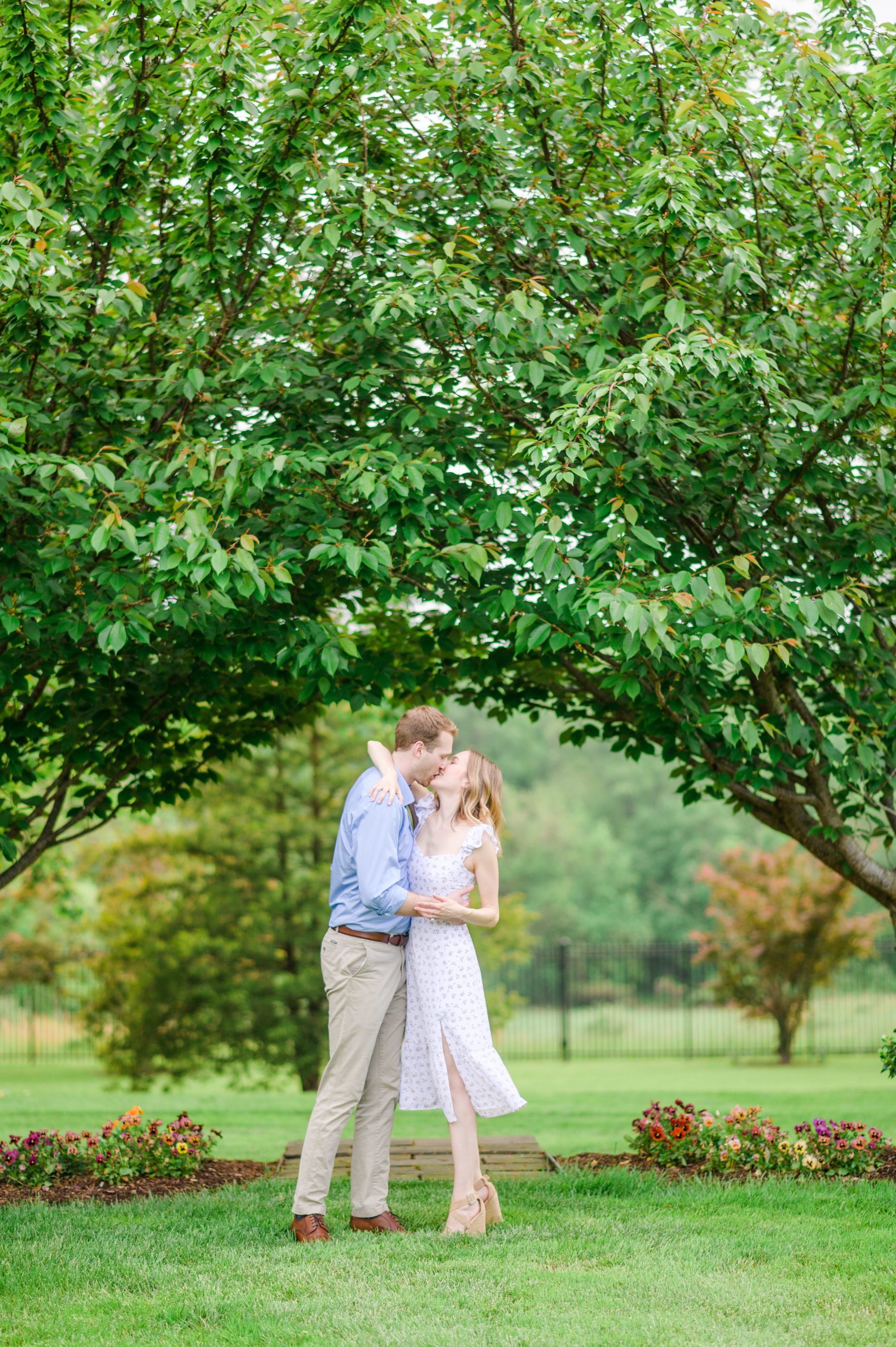 Engaged Couple smiles in the garden at Belmont Manor during a rainy sunset engagement photographed by Baltimore Wedding Photographer Cait Kramer