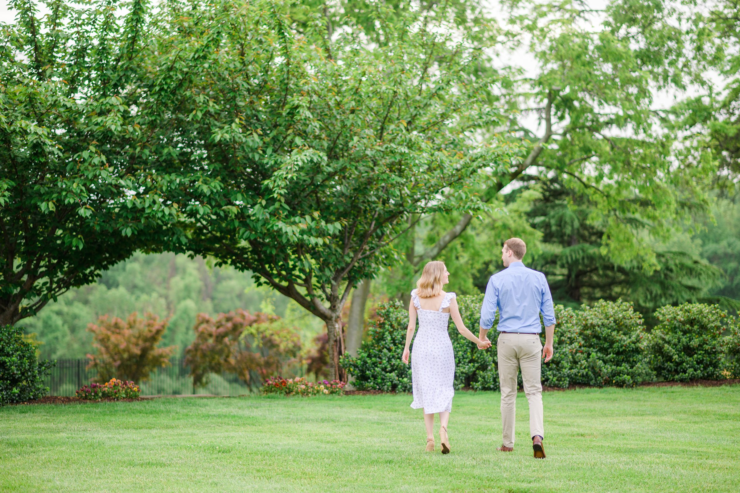 Engaged Couple smiles in the garden at Belmont Manor during a rainy sunset engagement photographed by Baltimore Wedding Photographer Cait Kramer