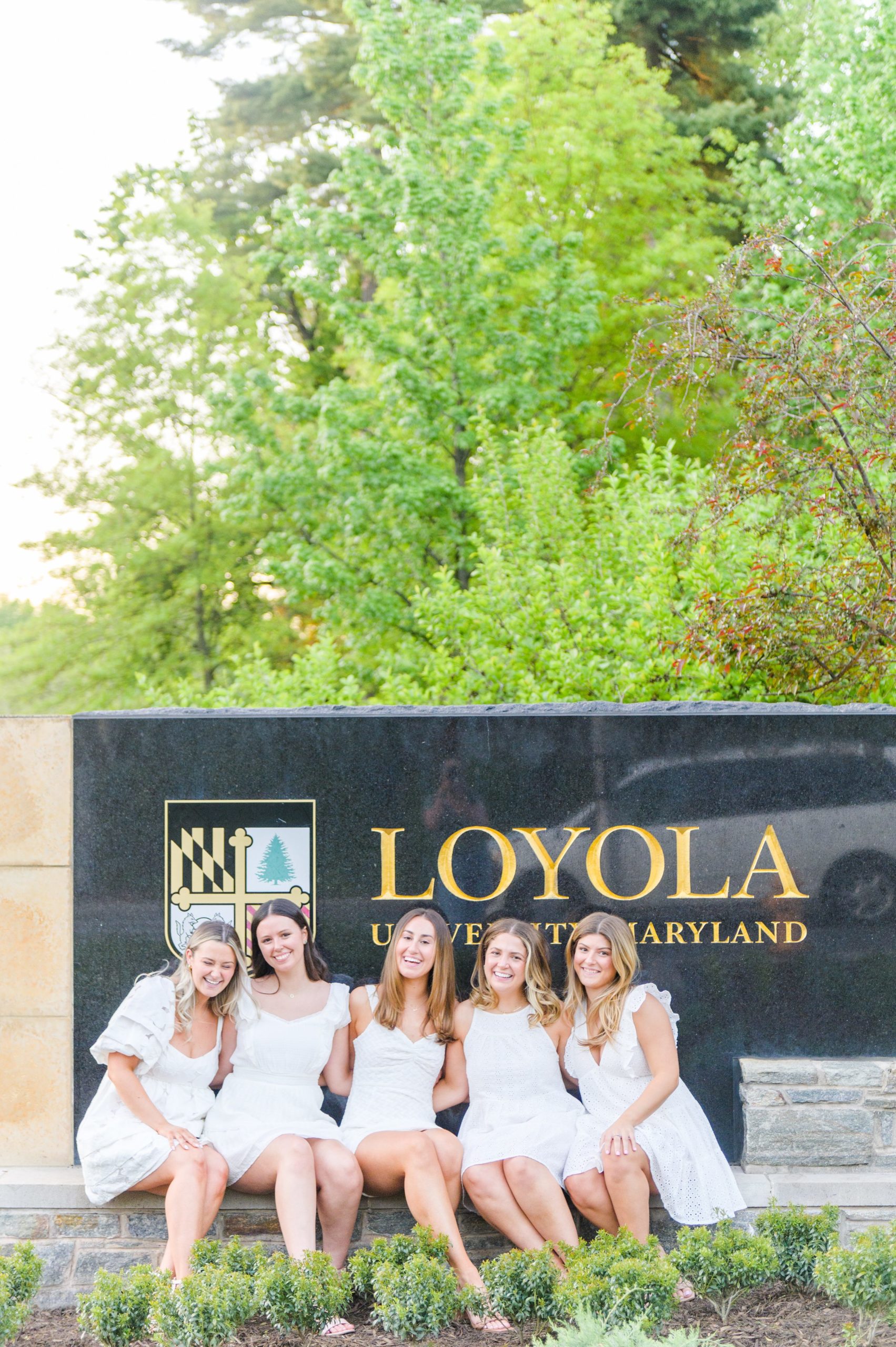 Loyola seniors pose on Loyola University Maryland's campus in graduation attire during Baltimore Grad Session photographed by Cait Kramer