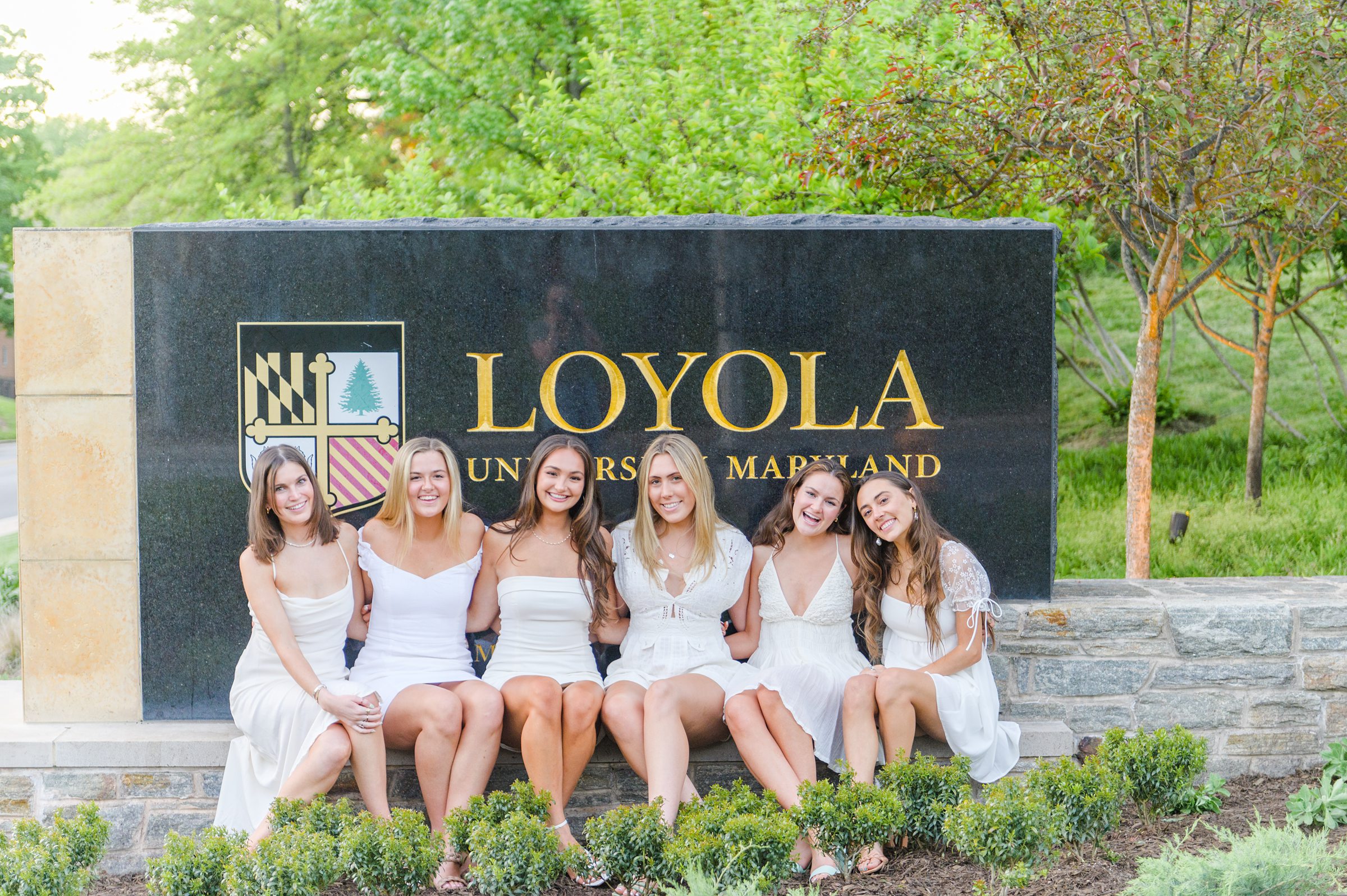 Loyola seniors pose on Loyola University Maryland's campus in graduation attire during Baltimore Grad Session photographed by Cait Kramer