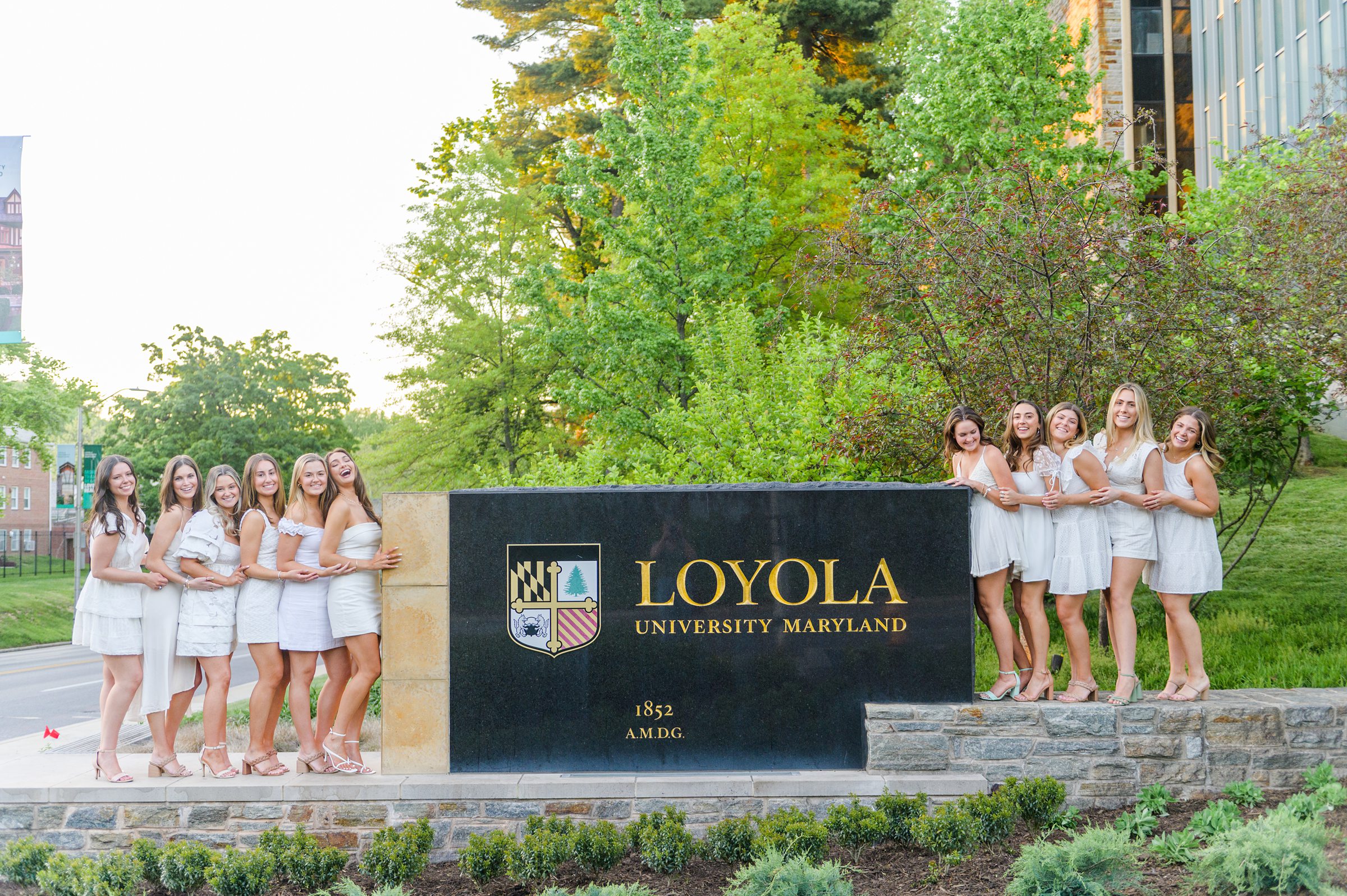 Loyola seniors pose on Loyola University Maryland's campus in graduation attire during Baltimore Grad Session photographed by Cait Kramer