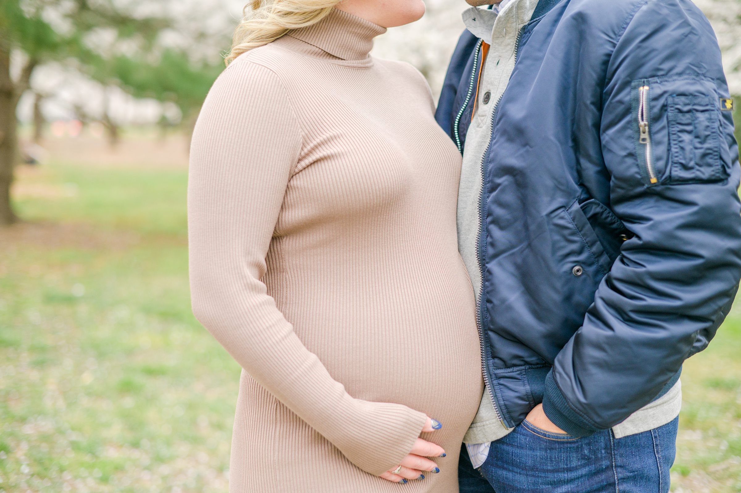 Mama and dad-to-be poses with her bump amongst the cherry blossoms at the Washington, DC Tidal Basin during a maternity session photographed by Cait Kramer Photography