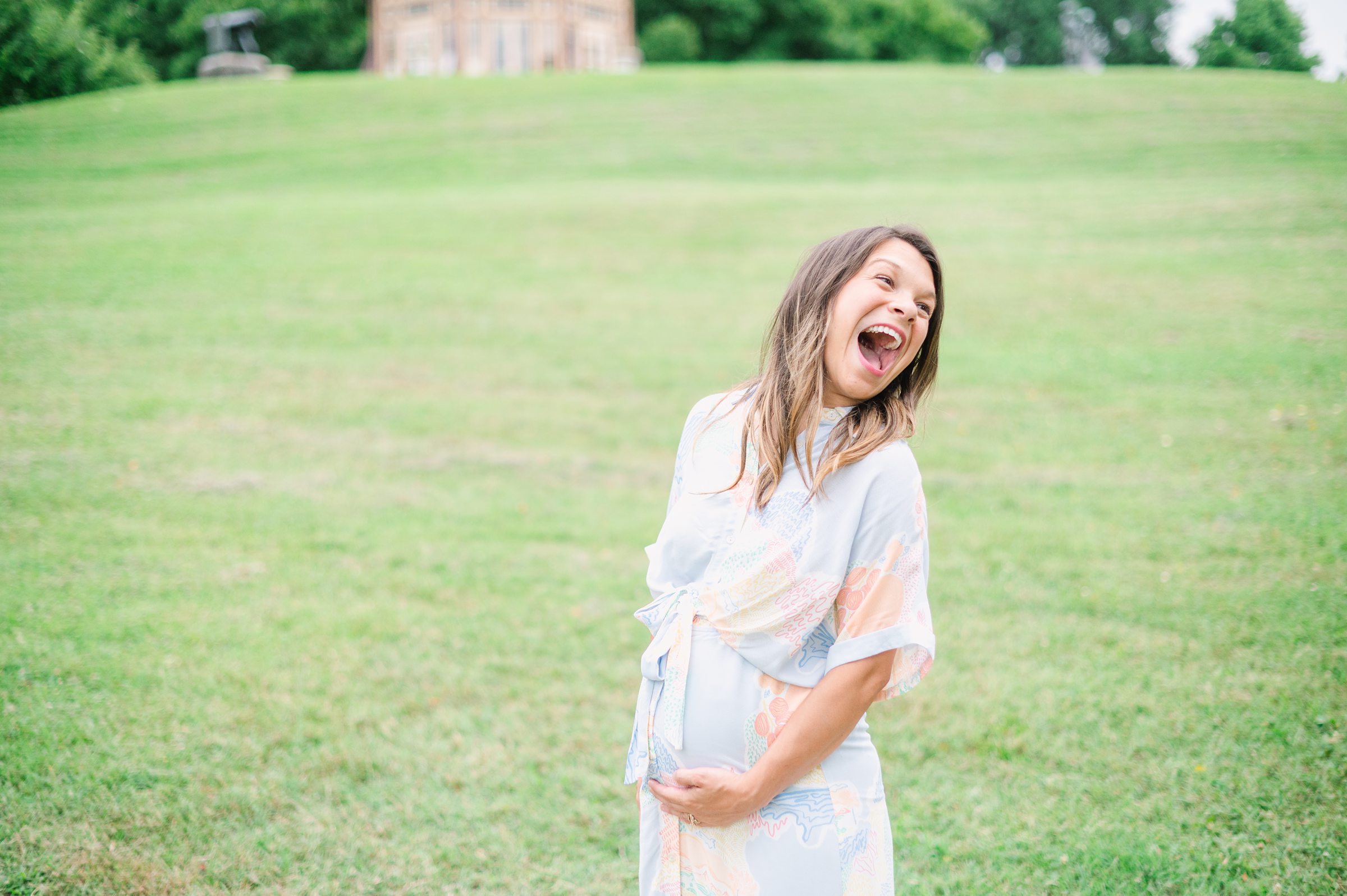 Expecting couple smiles during Patterson Park maternity session photographed by Baltimore Photographer Cait Kramer.