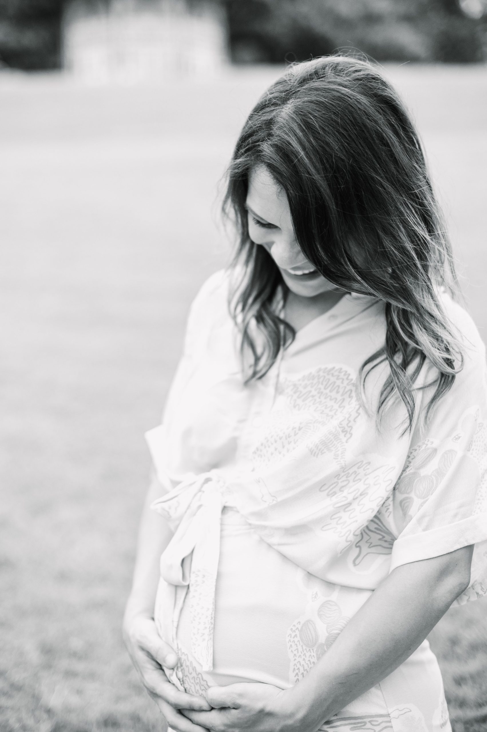 Expecting couple smiles during Patterson Park maternity session photographed by Baltimore Photographer Cait Kramer.