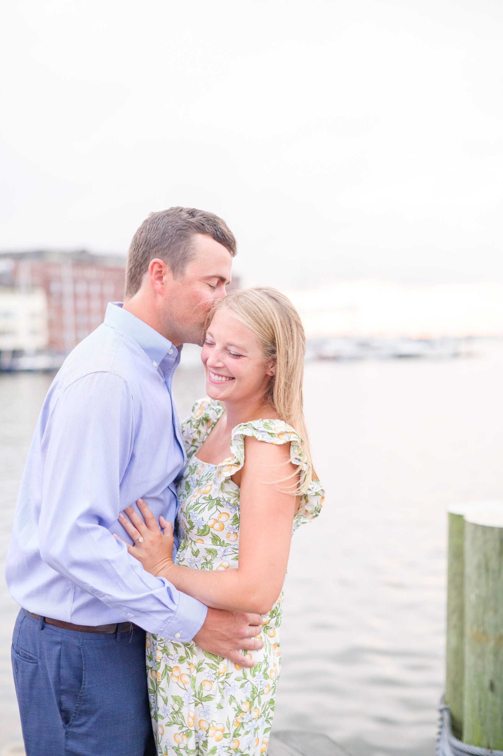 Couple snuggles on Broadway pier during Fells Point engagement session photographed by Baltimore wedding photographer Cait Kramer