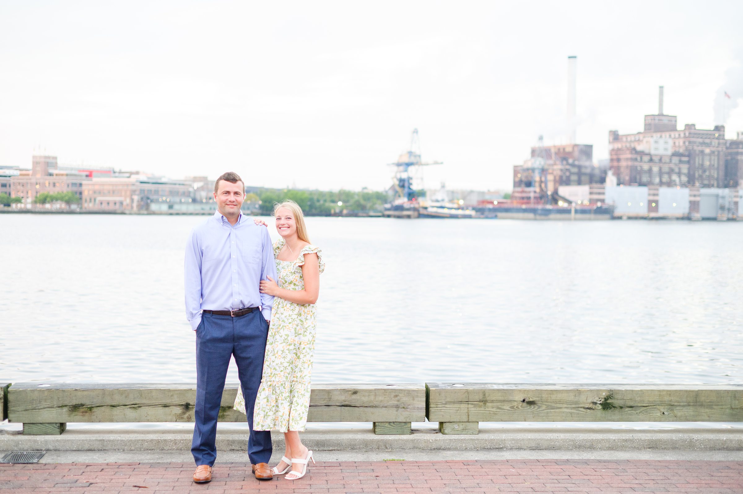 Couple smiles on Broadway pier during Fells Point engagement session photographed by Baltimore wedding photographer Cait Kramer