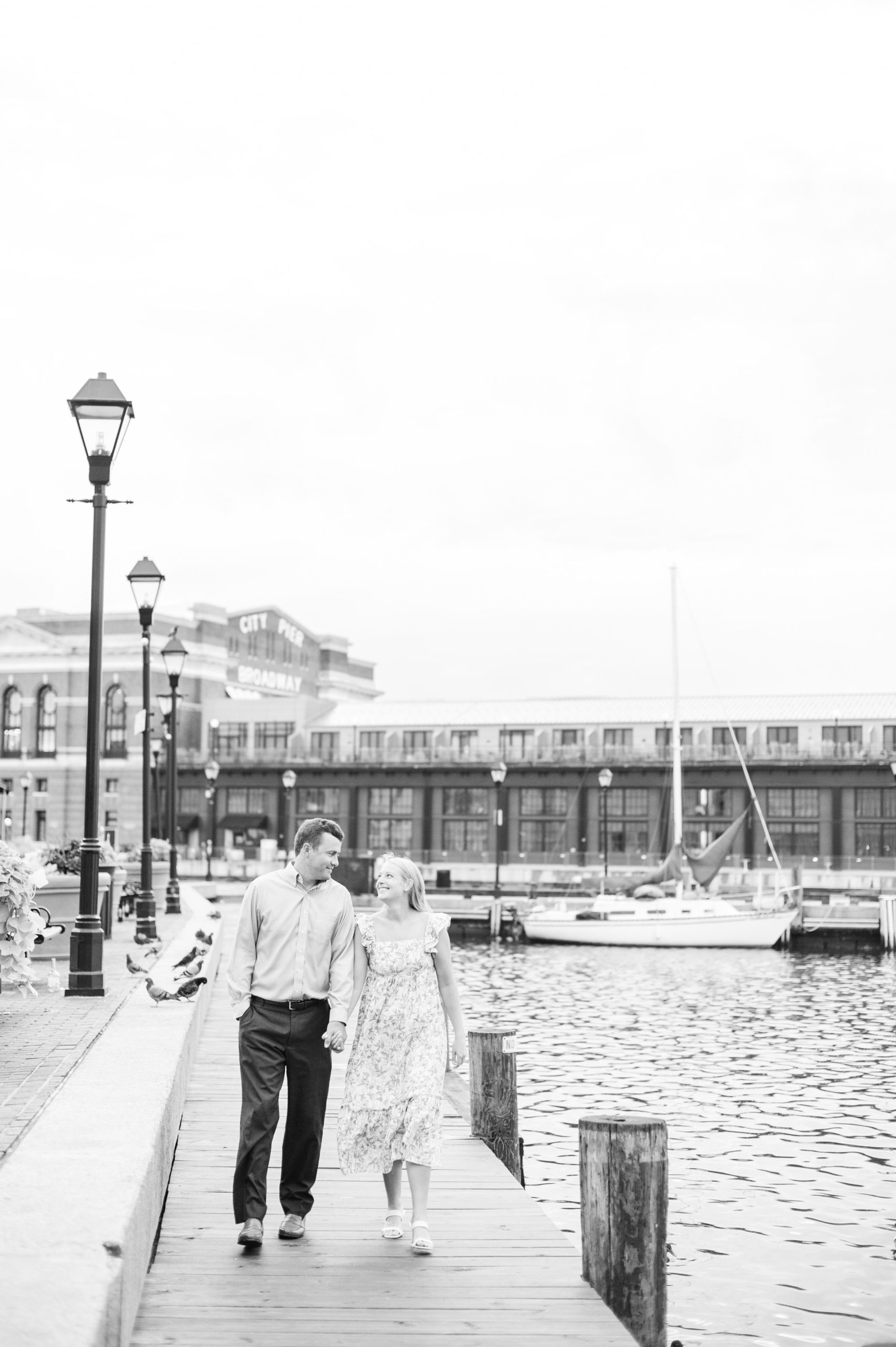 Couple poses near Broadway Pier during Fells Point engagement session photographed by Baltimore wedding photographer Cait Kramer