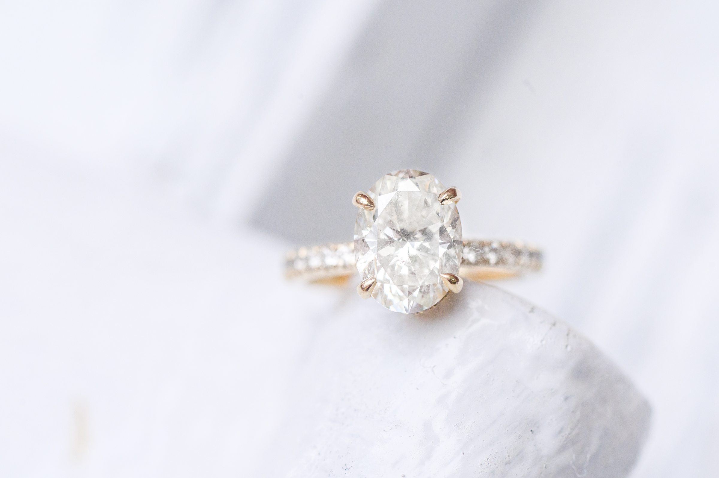 Bride's oval cut diamond engagement ring on a white background during Fells Point engagement session photographed by Baltimore wedding photographer Cait Kramer