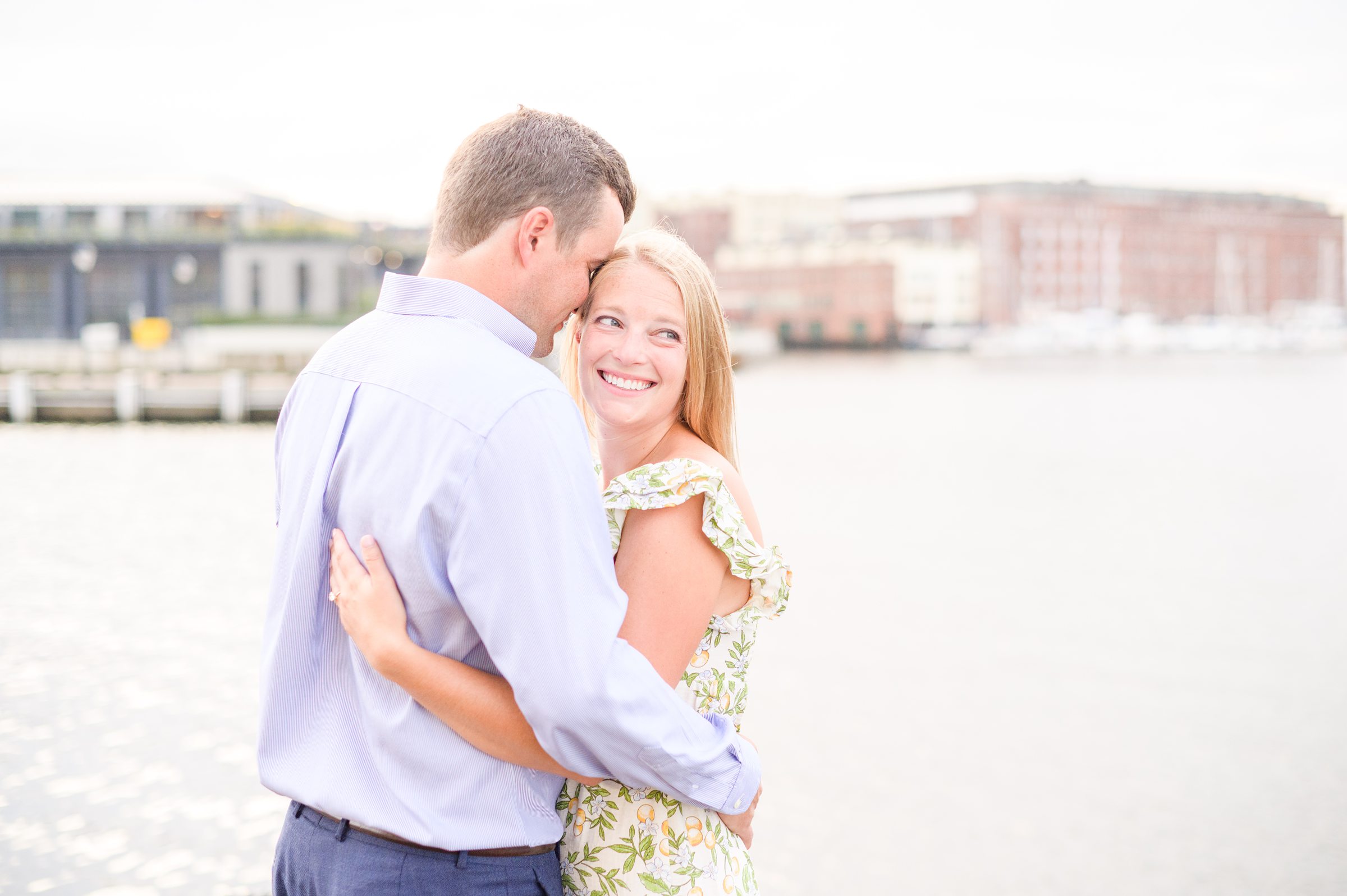 Couple poses near Henderson's Wharf during Fells Point engagement session photographed by Baltimore wedding photographer Cait Kramer