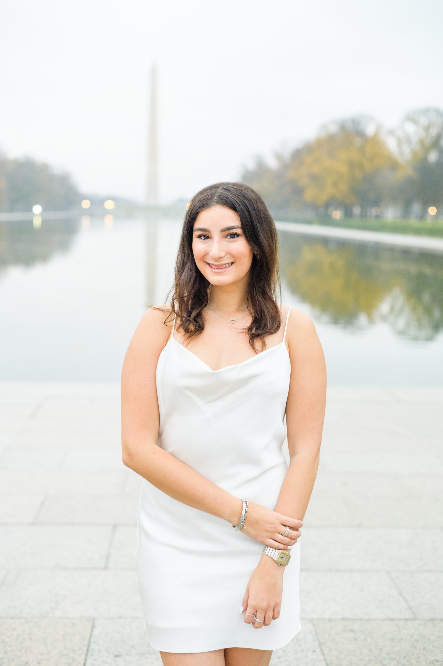 American University senior poses at the Lincoln Memorial in graduation attire during Washington DC Grad Session photographed by Cait Kramer