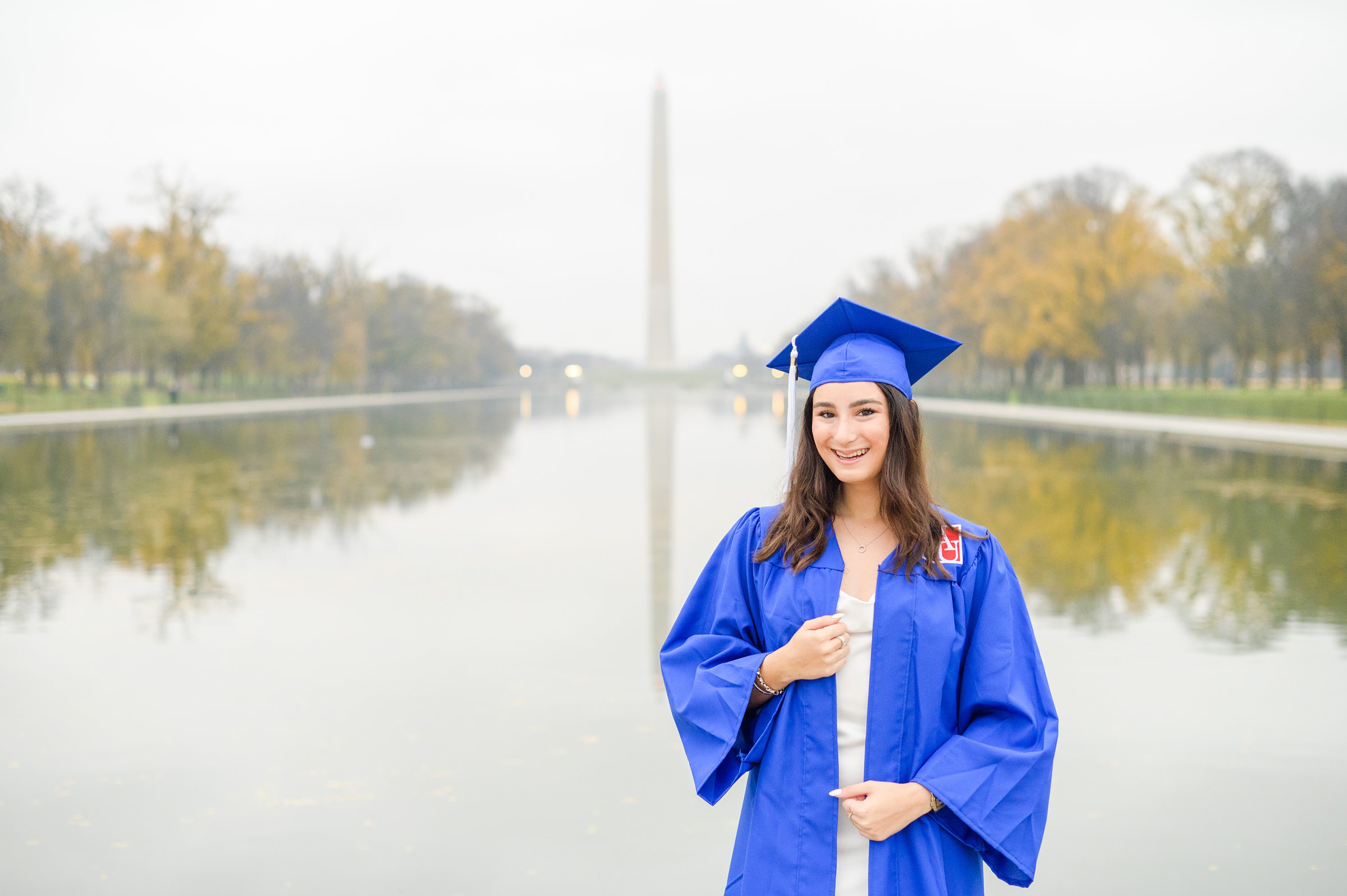 American University senior poses at the Lincoln Memorial in graduation attire during Washington DC Grad Session photographed by Cait Kramer