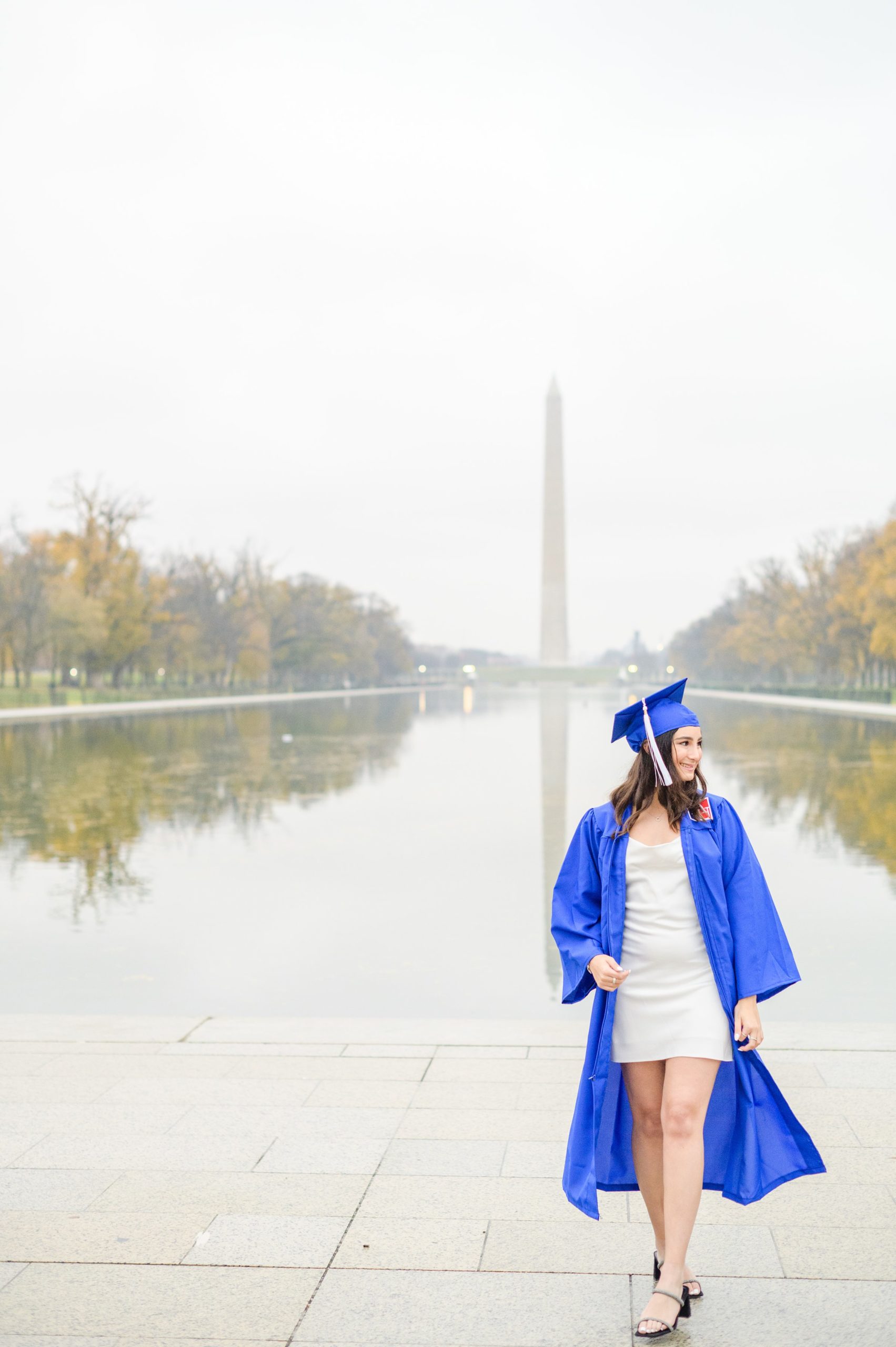 American University senior poses at the Lincoln Memorial in graduation attire during Washington DC Grad Session photographed by Cait Kramer