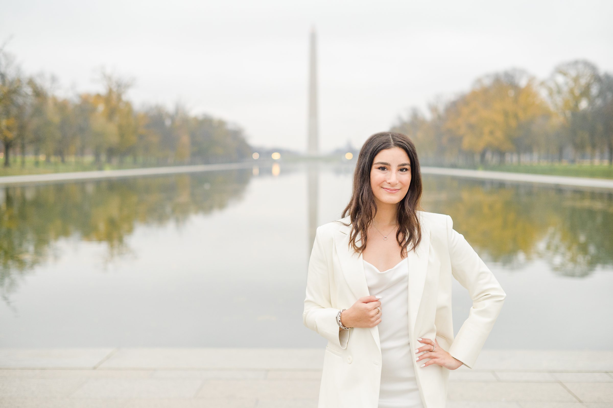 American University senior poses at the Lincoln Memorial in graduation attire during Washington DC Grad Session photographed by Cait Kramer