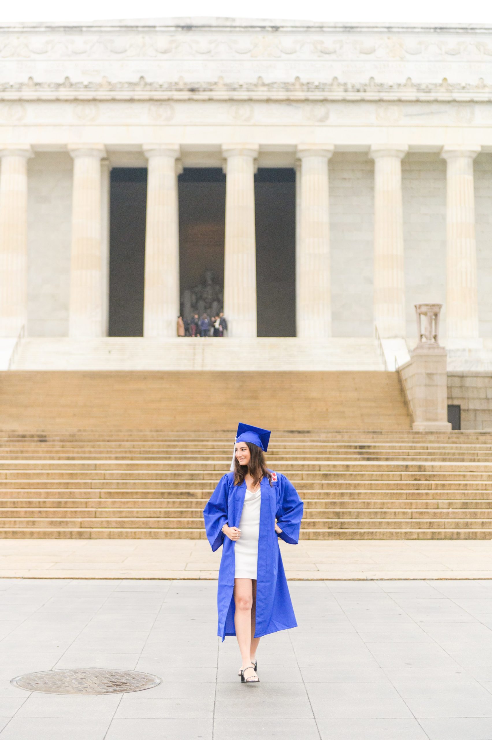 American University senior poses at the Lincoln Memorial in graduation attire during Washington DC Grad Session photographed by Cait Kramer