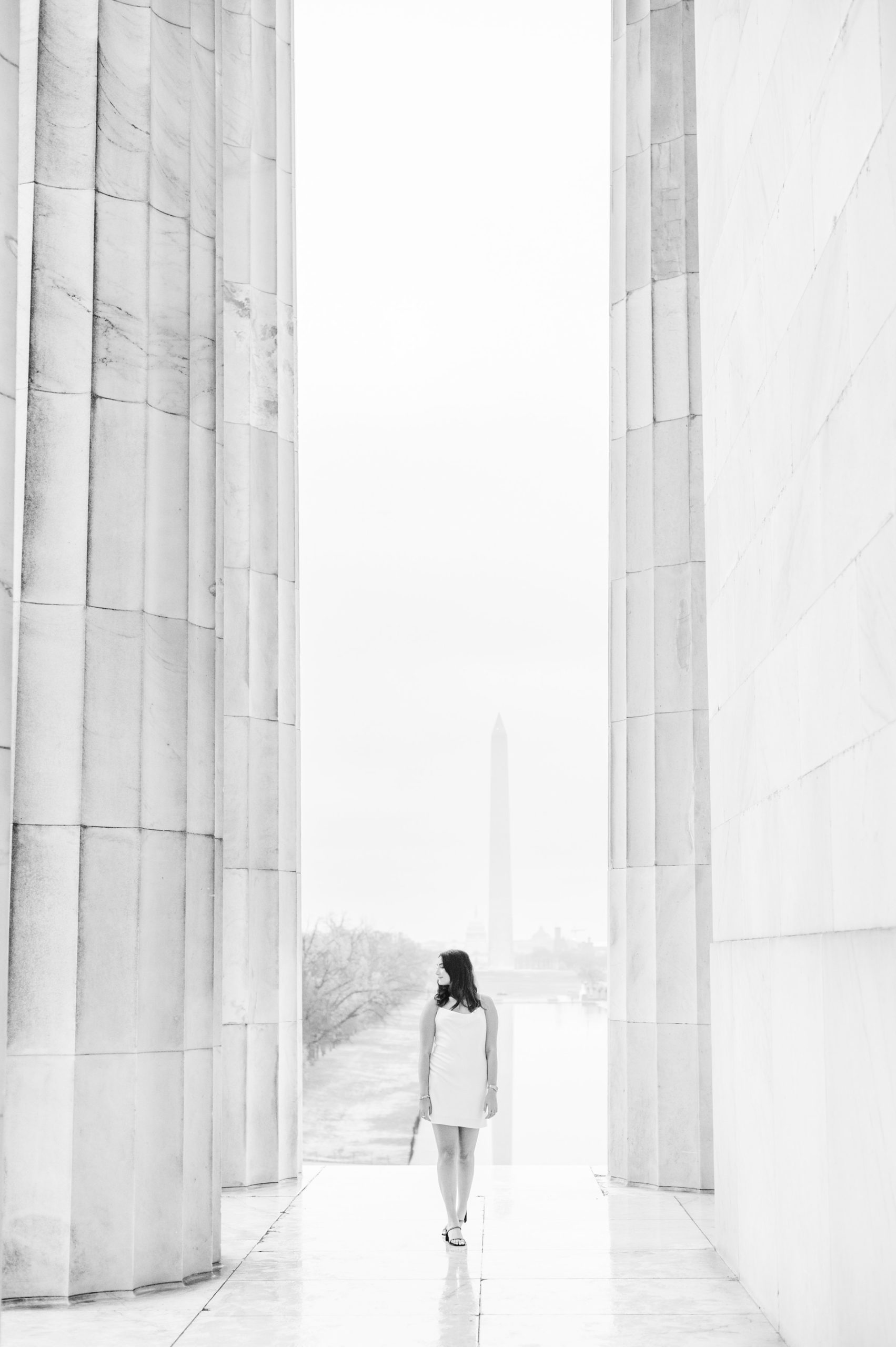 American University senior poses at the Lincoln Memorial in graduation attire during Washington DC Grad Session photographed by Cait Kramer