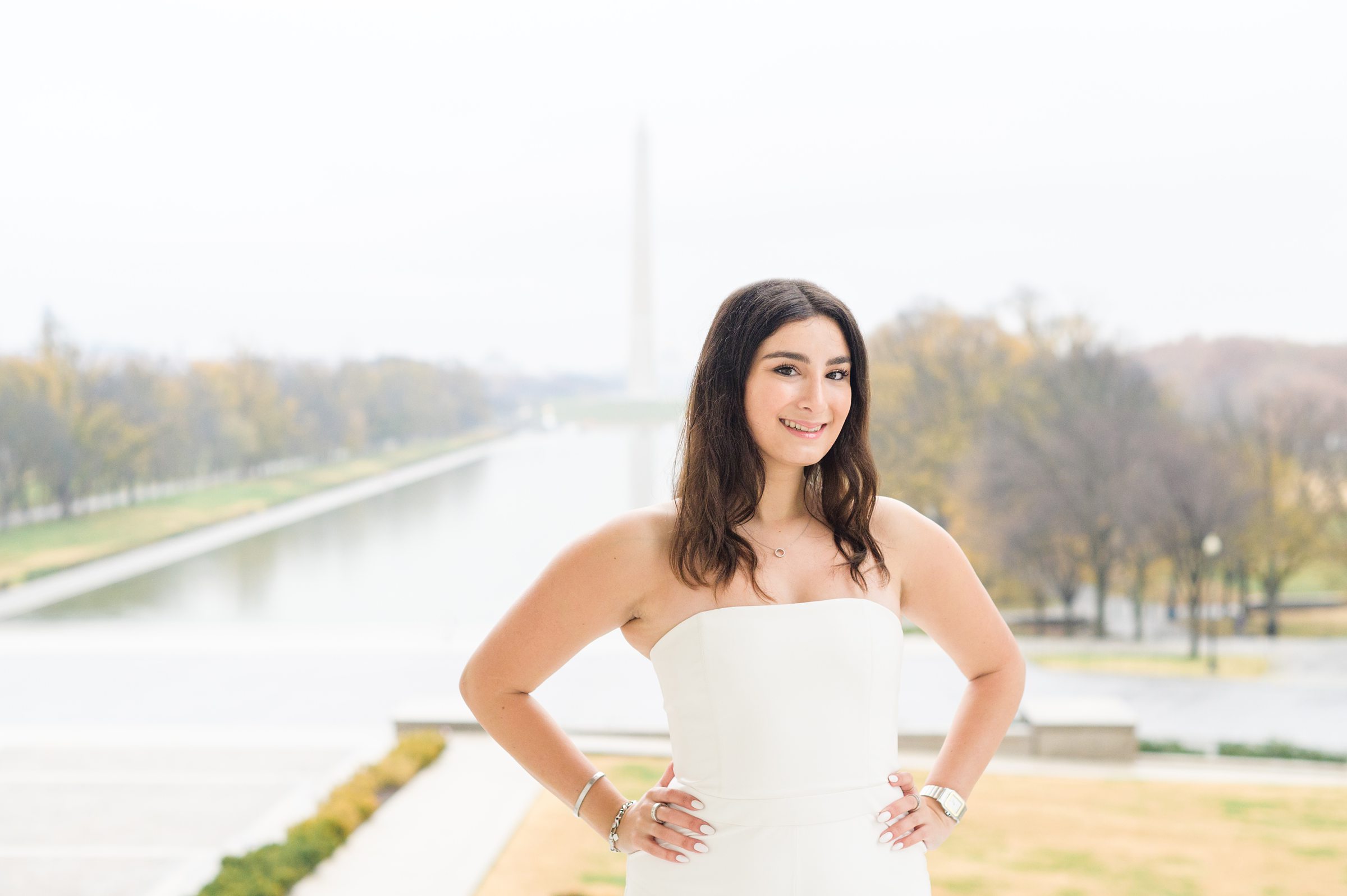 American University senior poses at the Lincoln Memorial in graduation attire during Washington DC Grad Session photographed by Cait Kramer