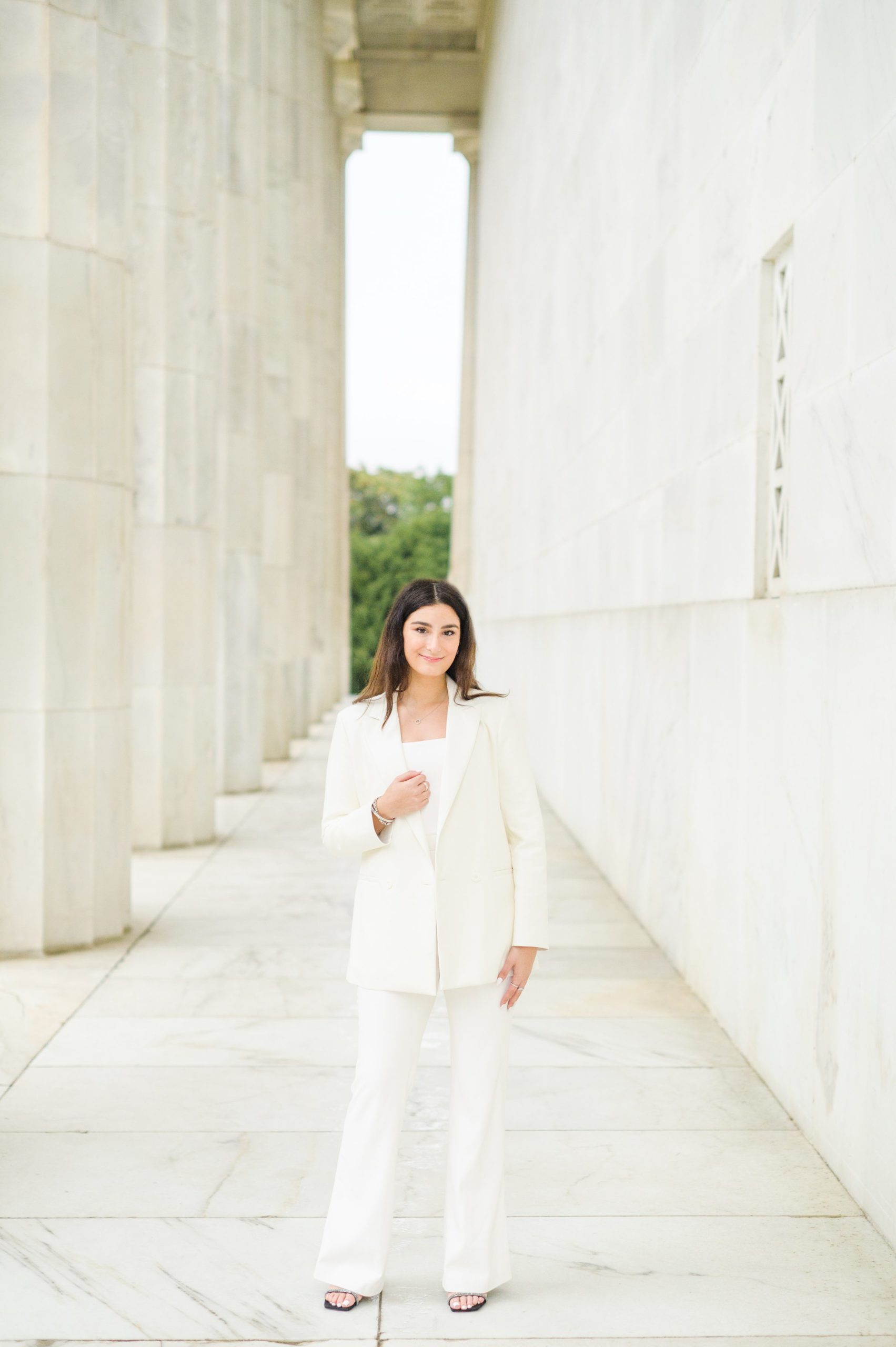 American University senior poses at the Lincoln Memorial in graduation attire during Washington DC Grad Session photographed by Cait Kramer