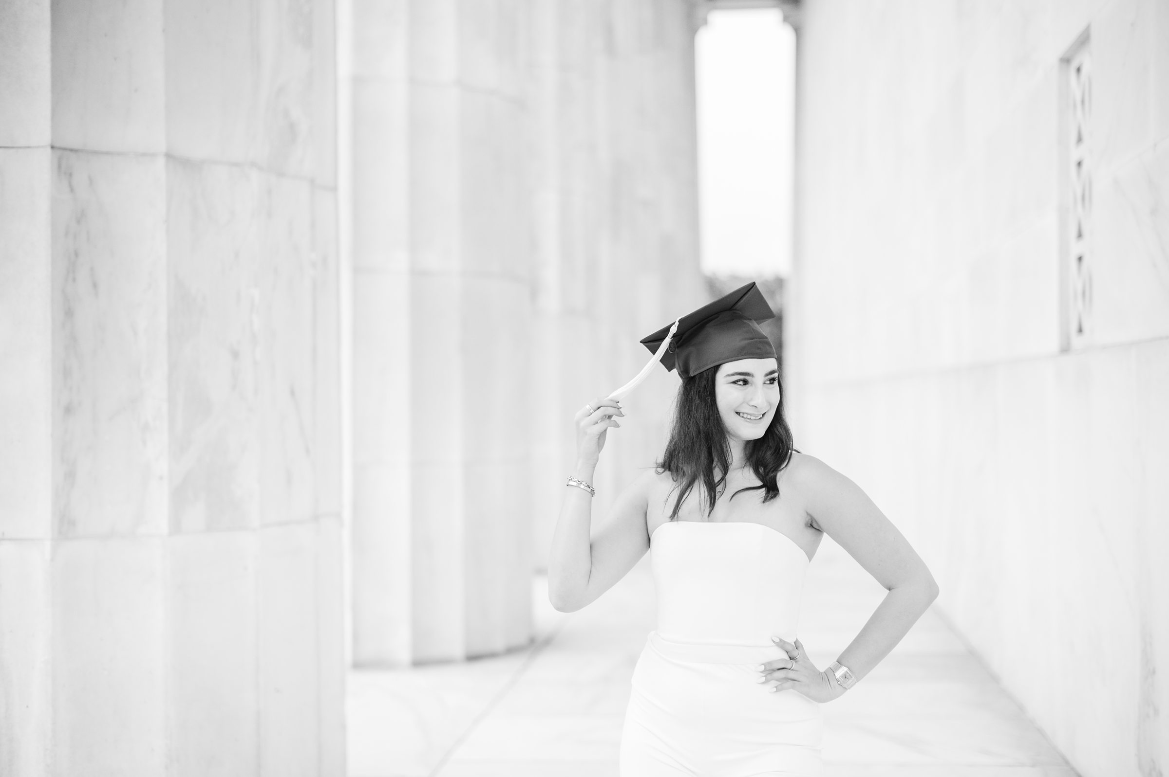 American University senior poses at the Lincoln Memorial in graduation attire during Washington DC Grad Session photographed by Cait Kramer