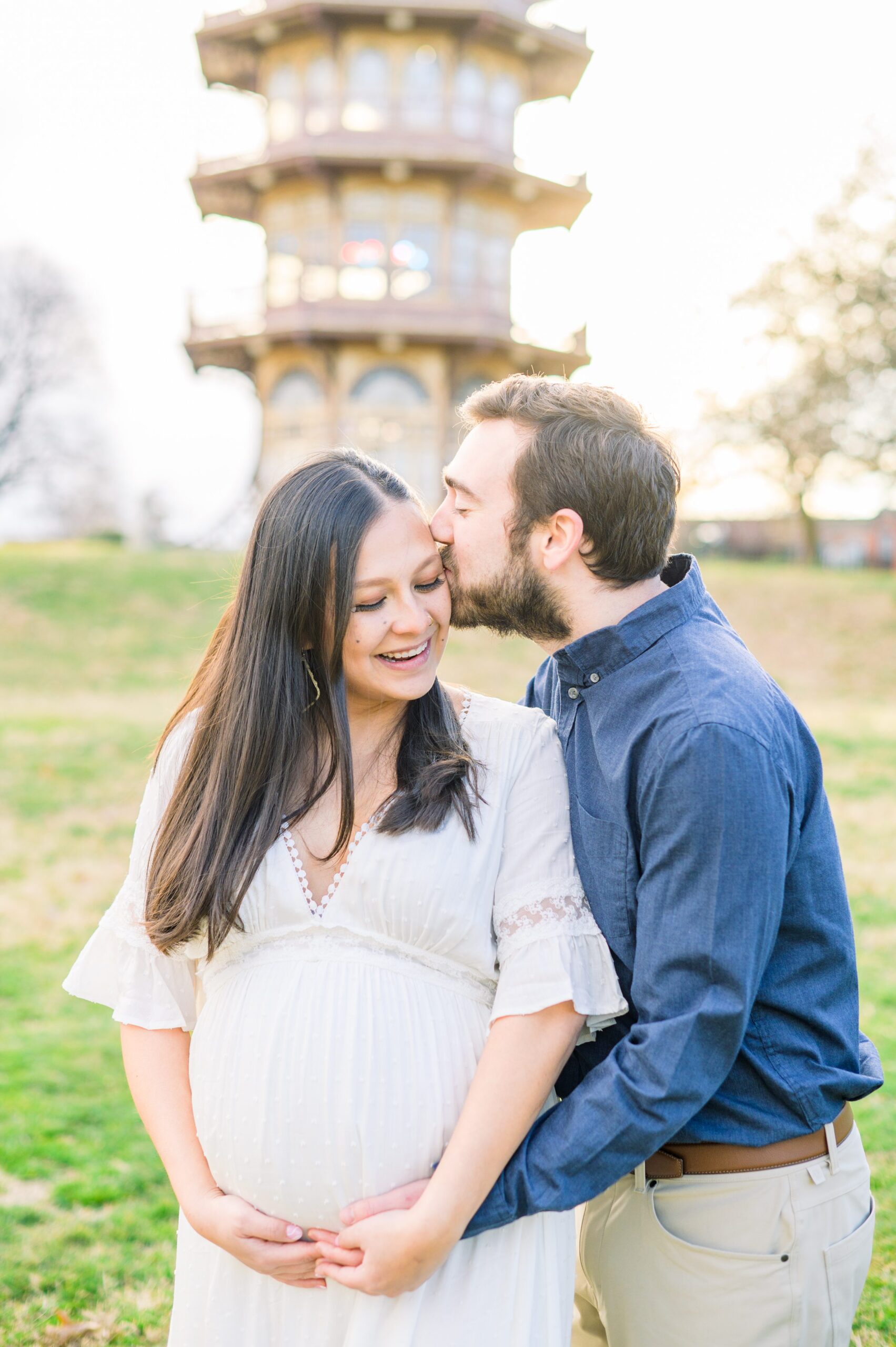 Abby and Nick's maternity photos in Patterson Park in Baltimore County featuring a stunning golden hour and beautiful pink trees.