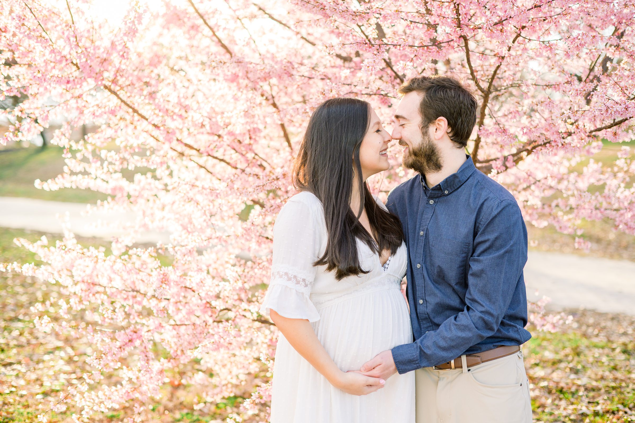 Abby and Nick's maternity photos in Patterson Park in Baltimore County featuring a stunning golden hour and beautiful pink trees.