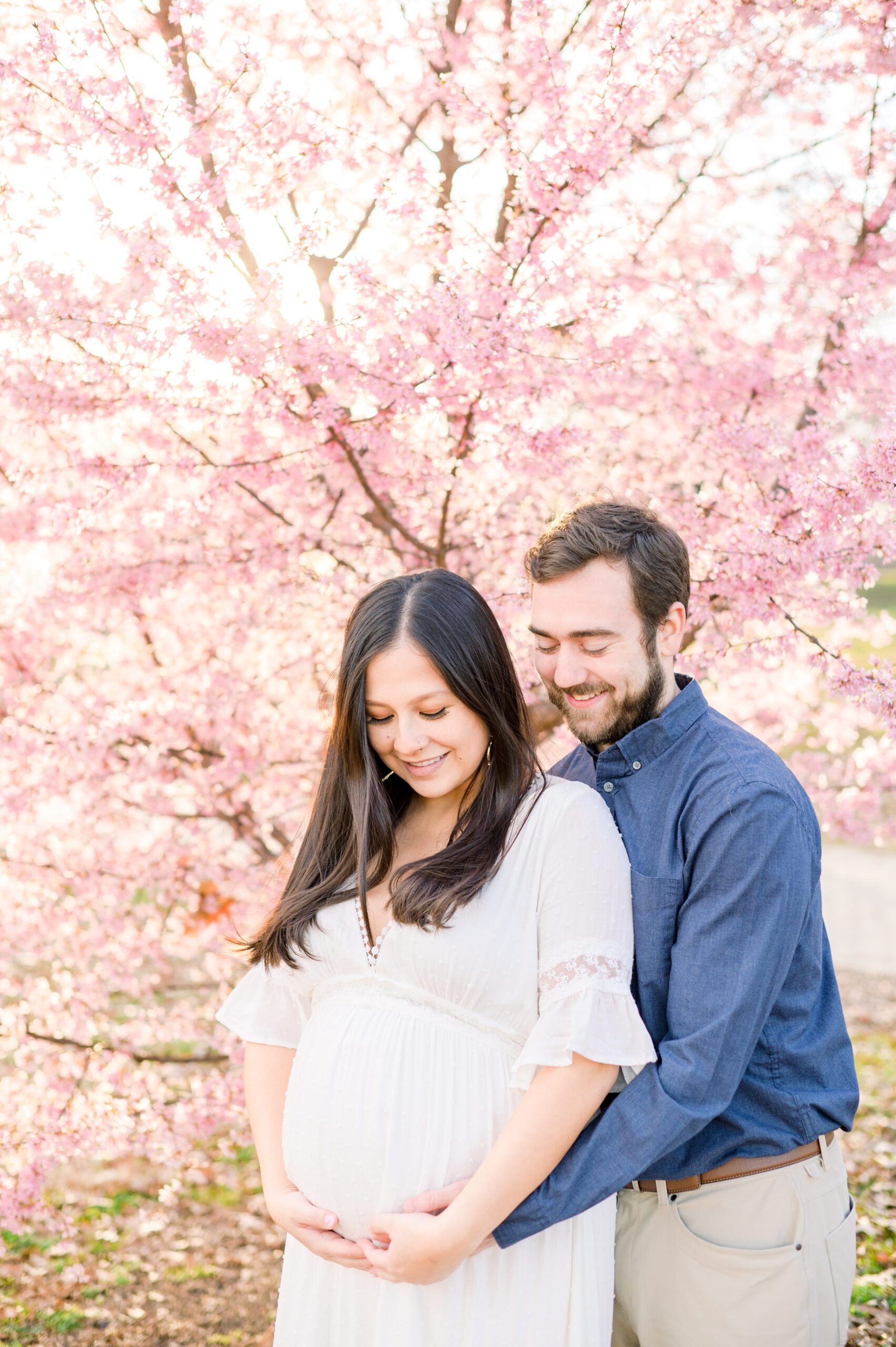 Abby and Nick's maternity photos in Patterson Park in Baltimore County featuring a stunning golden hour and beautiful pink trees.