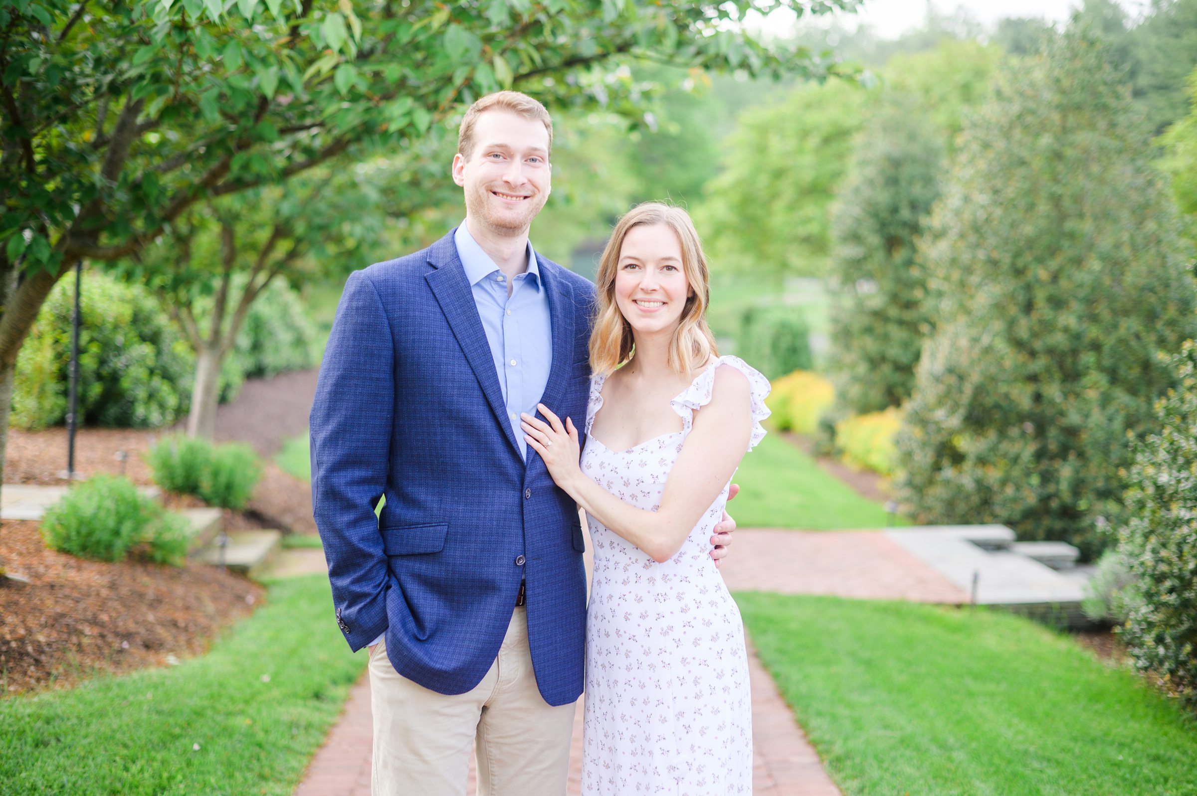 Engaged Couple smiles in the garden at Belmont Manor during a rainy sunset engagement photographed by Baltimore Wedding Photographer Cait Kramer