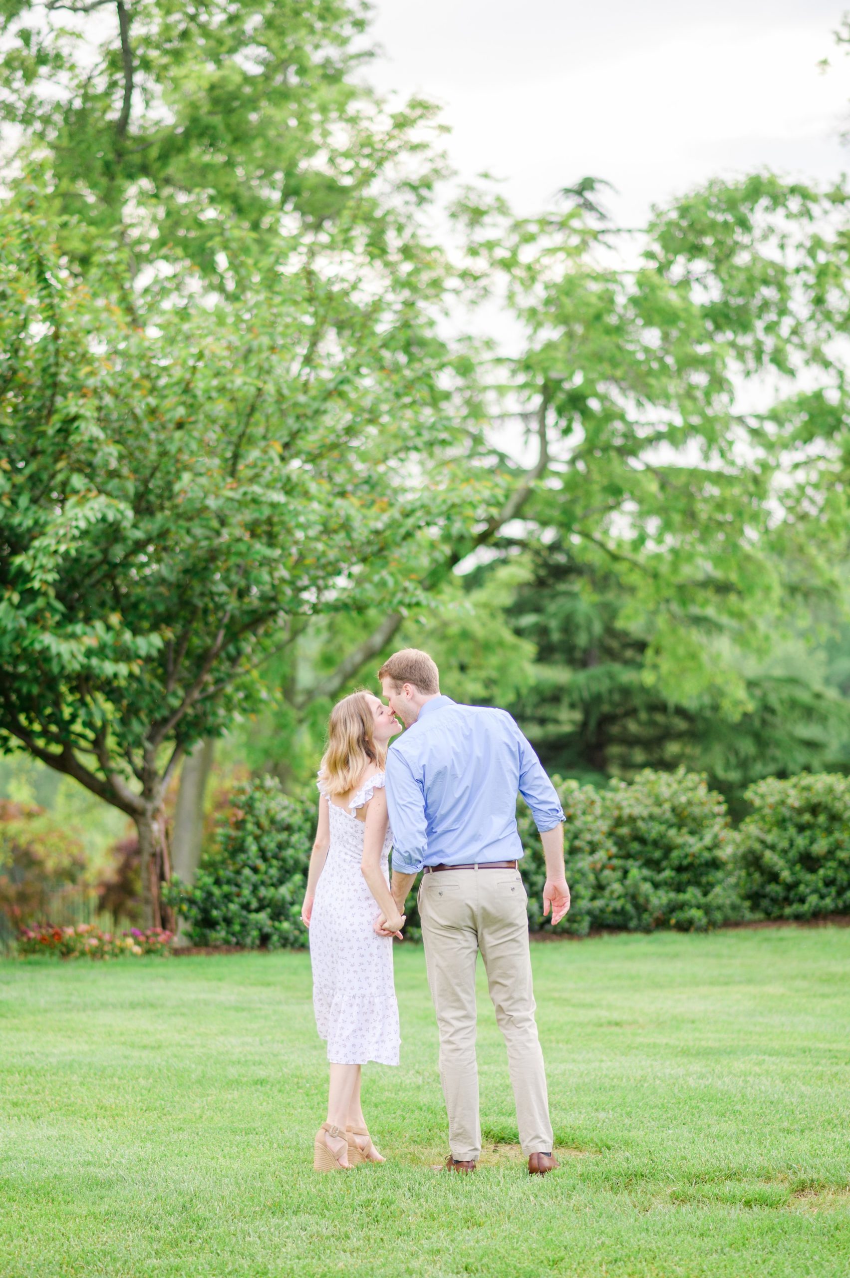 Engaged Couple smiles in the garden at Belmont Manor during a rainy sunset engagement photographed by Baltimore Wedding Photographer Cait Kramer