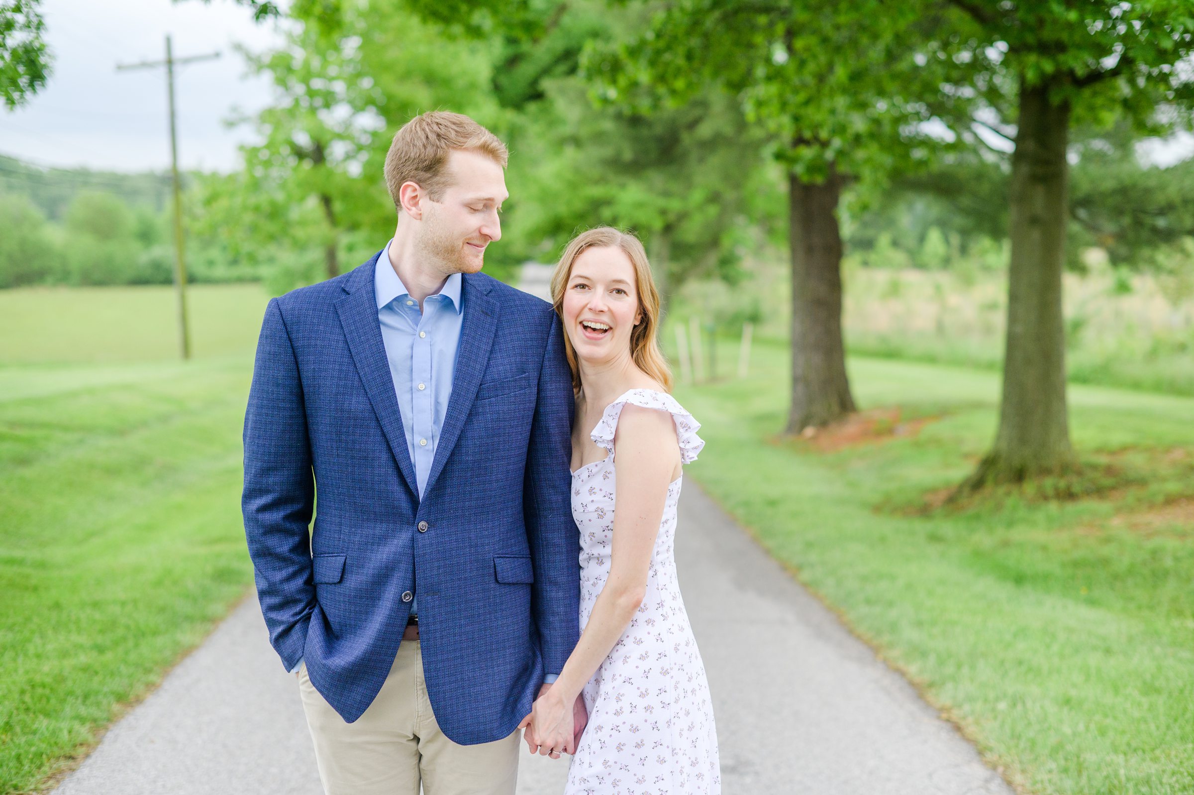 Engaged Couple poses on the treelined driveway at Belmont Manor during a rainy sunset engagement photographed by Baltimore Wedding Photographer Cait Kramer