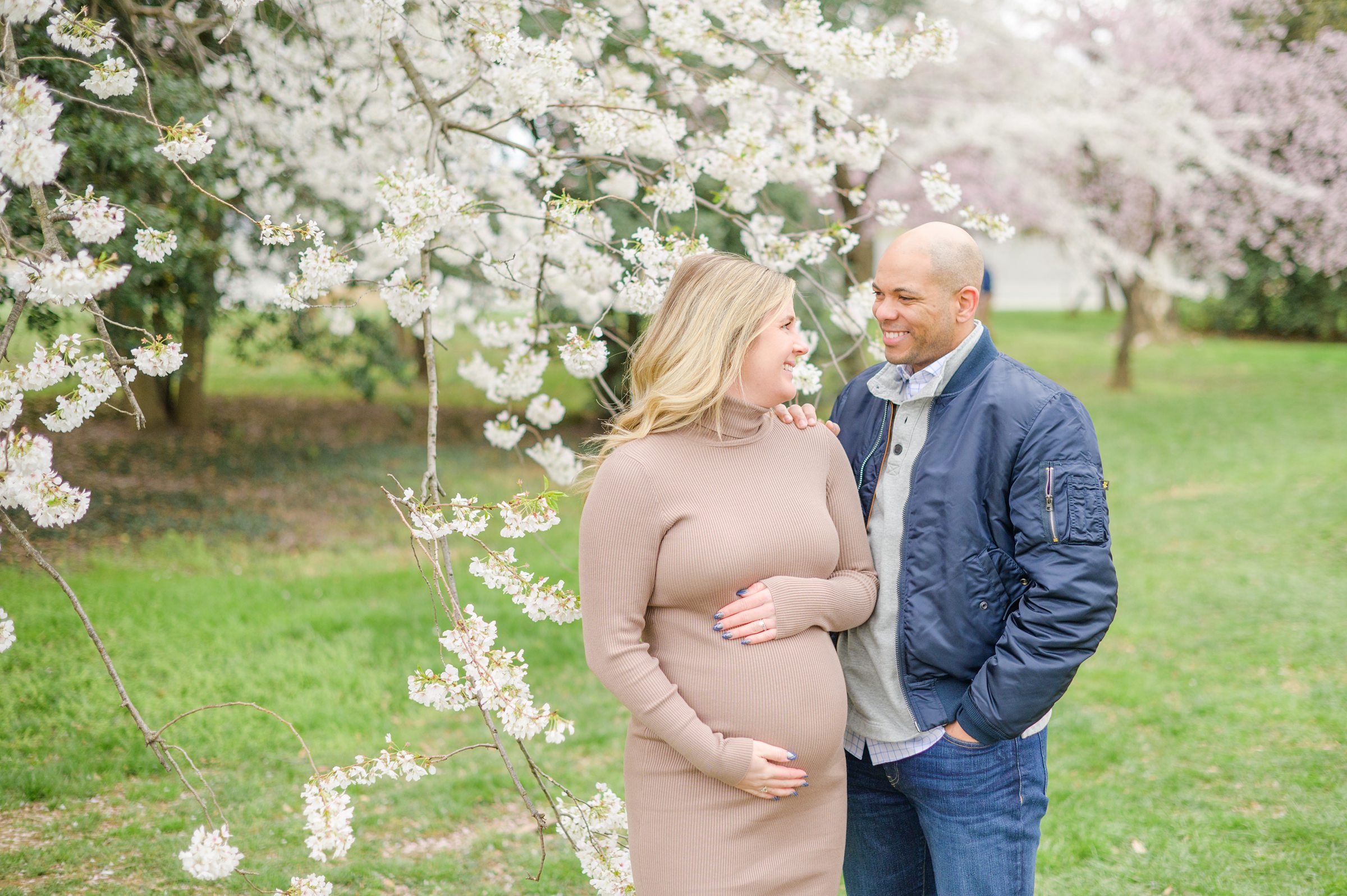 Mama and dad-to-be poses with her bump amongst the cherry blossoms at the Washington, DC Tidal Basin during a maternity session photographed by Cait Kramer Photography