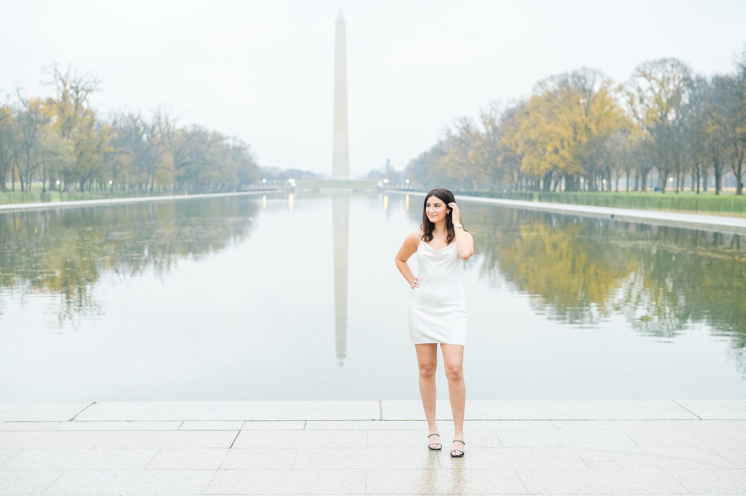 American University senior poses at the Lincoln Memorial in graduation attire during Washington DC Grad Session photographed by Cait Kramer