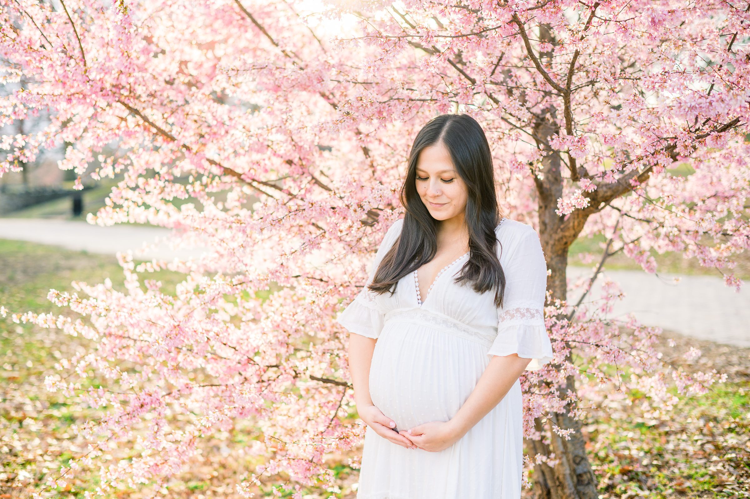 Abby and Nick's maternity photos in Patterson Park in Baltimore County featuring a stunning golden hour and beautiful pink trees.