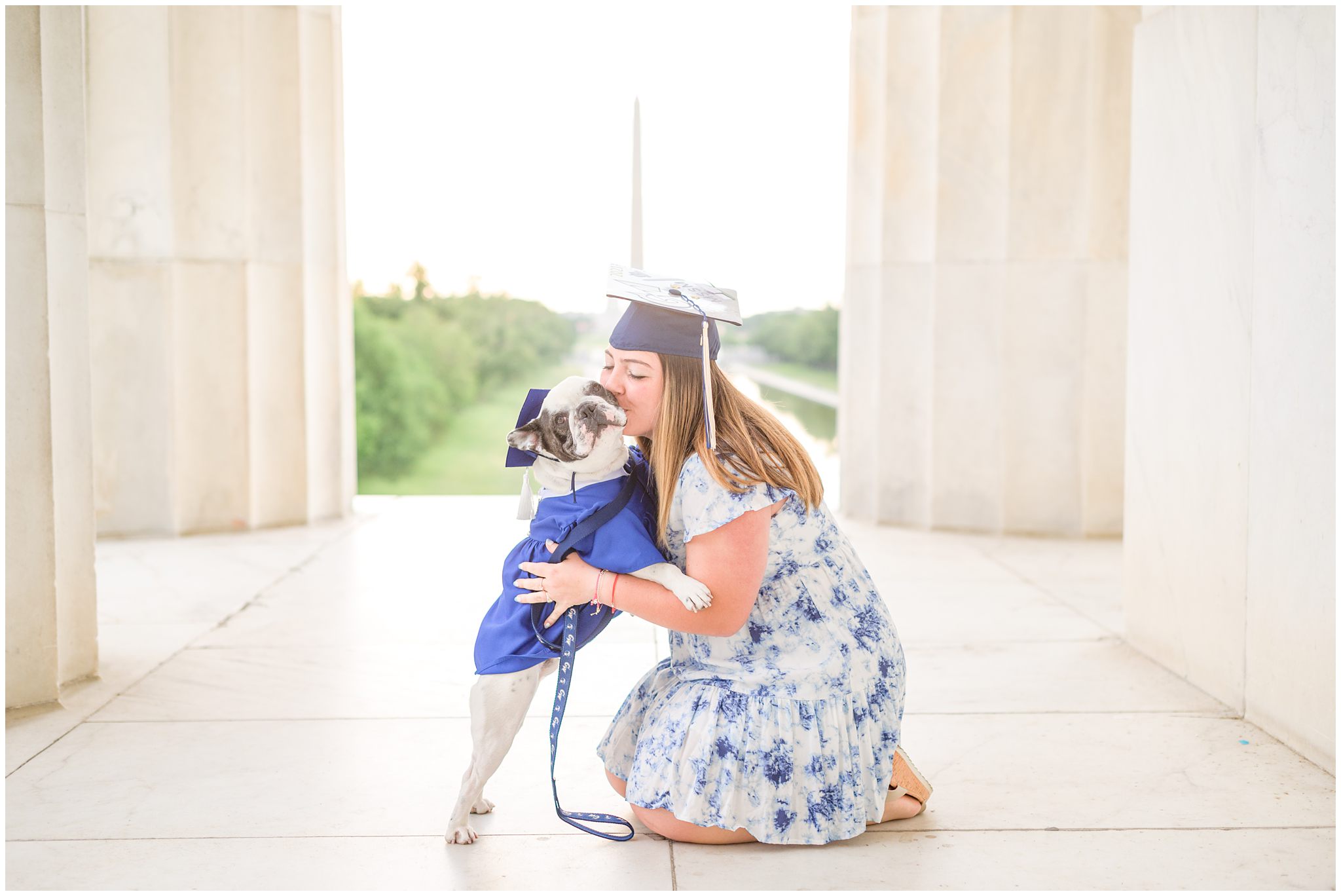 College graduate poses with her puppy in a graduation cap on the Lincoln Memorial in Washington DC